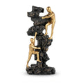 Rock climbing sculpture featuring two gold-finished human figures scaling a textured black cliff face