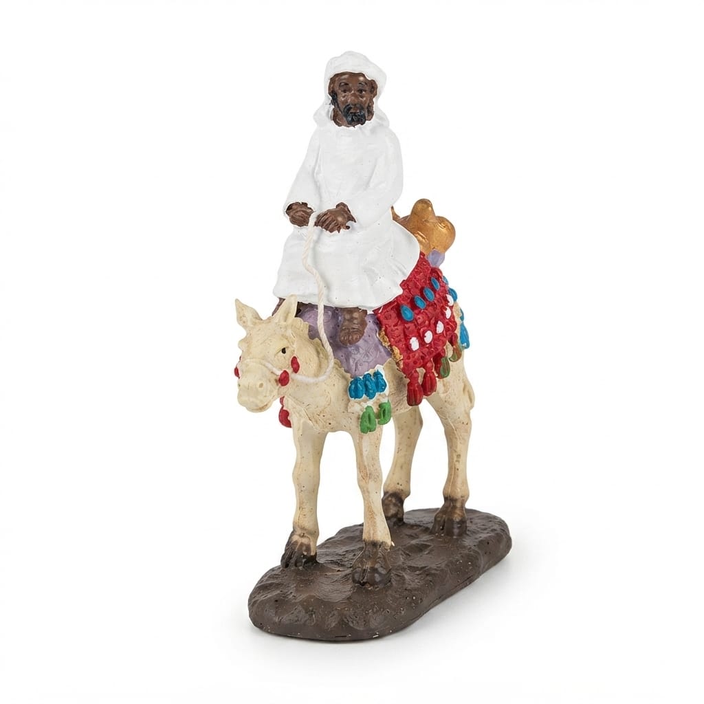 Figurine of a person in white traditional attire riding a decorated camel