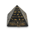 Black and gold carved pyramid paperweight featuring hieroglyphic bands and a winged scarab emblem at the base