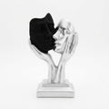 Silver-finish dual-hand sculpture cradling two distinct facial masks, one in matte black and one in smooth silver