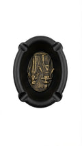 Black oval ashtray featuring a golden relief of ancient Egyptian deities on the inner bottom
