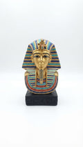 King Tutankhamun golden bust figurine with a turquoise and blue striped nemes headdress, detailed collar, and an inscribed black base
