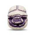 White and purple scarab beetle figurine featuring the Eye of Horus and hieroglyphics